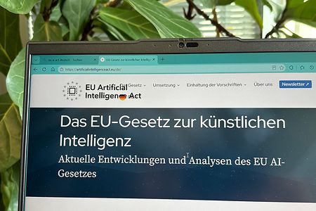 Laptop auf einem Schreibtisch, auf dem Display die Website zum EU AI-Gesetz