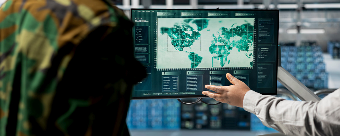 Nahaufnahme von Milit&auml;rexperten, die in einem Rechenzentrum auf einer digitalen Karte auf relevante Regionen zeigen.