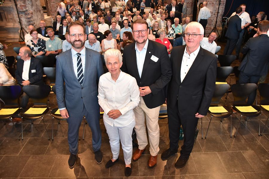 Gruppenfoto im Saal. Im Hintergrund sind die Sitzreihen der Besucher zu sehen.
