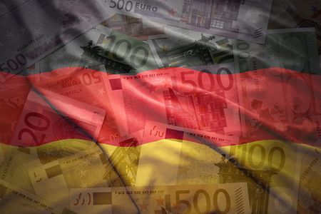 Euro-Geldscheine hinter transparenter Deutschland-Fahne.