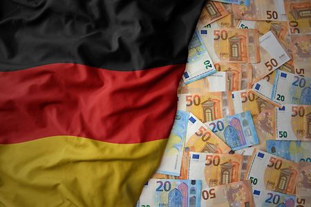 Euro-Geldscheine neben Deutschland-Fahne.