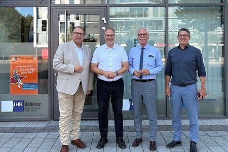 Vier Herren posieren vor einem Geb&auml;ude.