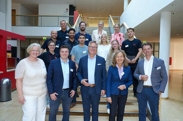 Gruppenfoto von Mitarbeitenden und G&auml;sten auf einer Treppe.