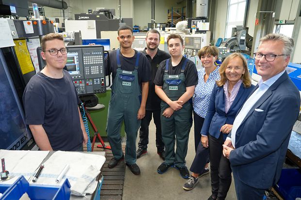 Gruppenfoto von Mitarbeitenden und G&auml;sten in einer Fertigungshalle.