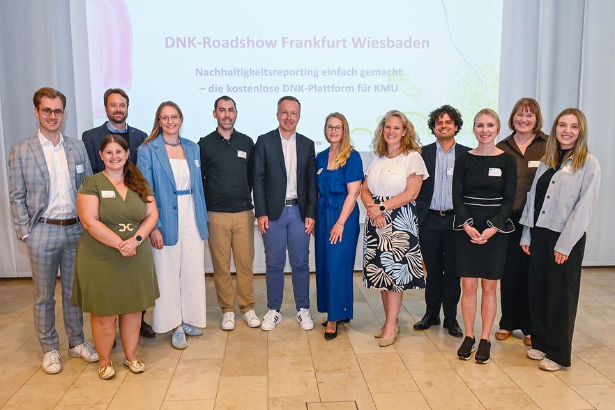 Mehrere Personen vor einer Leinwand, Pr&auml;asentation mit Titel "DNK-Roadshow Frankfurt Wiesbaden"
