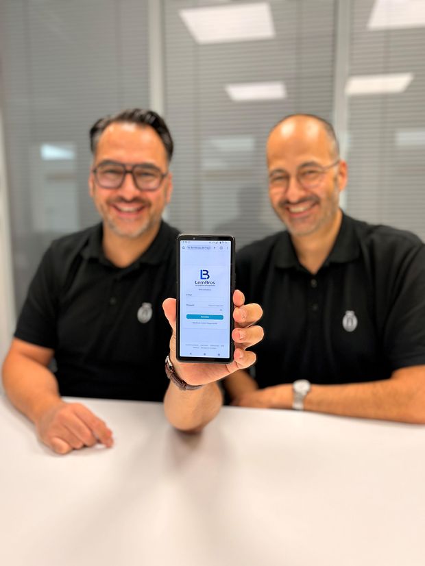 Zwei Männer halten Handy in die Kamera.