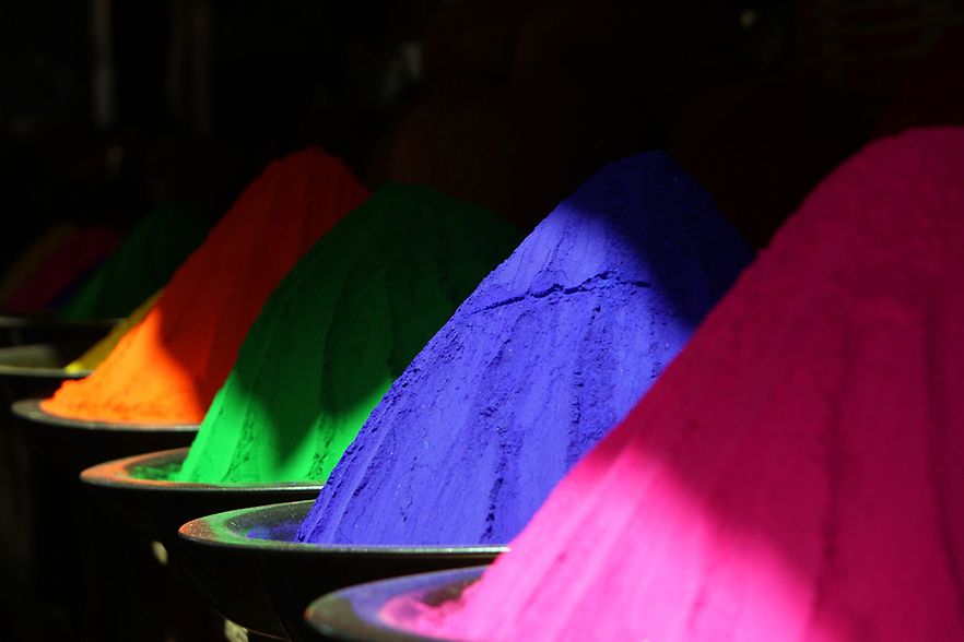 Schalen mit leuchtend bunten Farbpigmenten in Pink, Blau, Gr&uuml;n, Orange und Gelb.