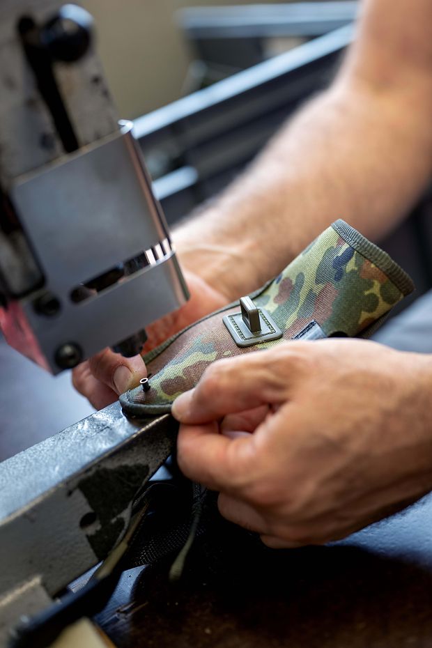 Ein Stoff in Flecktarn wird auf einer Nähmaschine bearbeitet. 