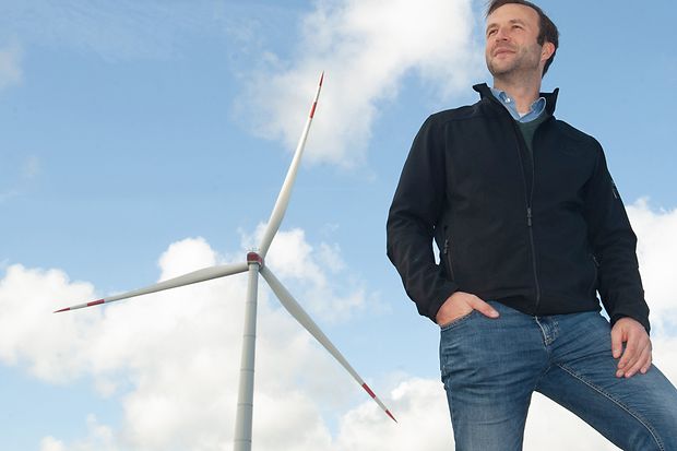 Tjark Beye stehend vor einer Windkraftanlage.