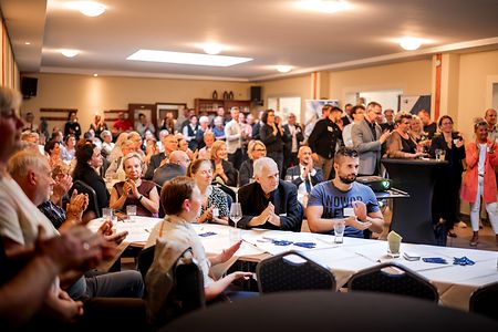 viele Personen in einem Konferenzraum applaudieren