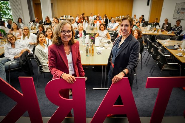 Zwei Frauen bei einer Netzwerkveranstaltung mit zahlreichen Teilnehmerinnen