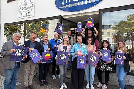Gruppe vor Modehaus mit Werbematerialen Heimat-Shoppen