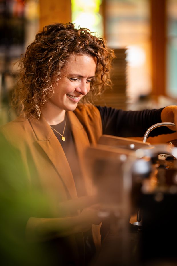 Frau lächelnd an Kaffeemaschine