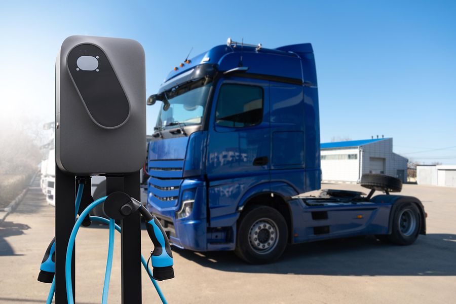Ein Lkw an einer Ladesäule auf einem Logistikgelände.