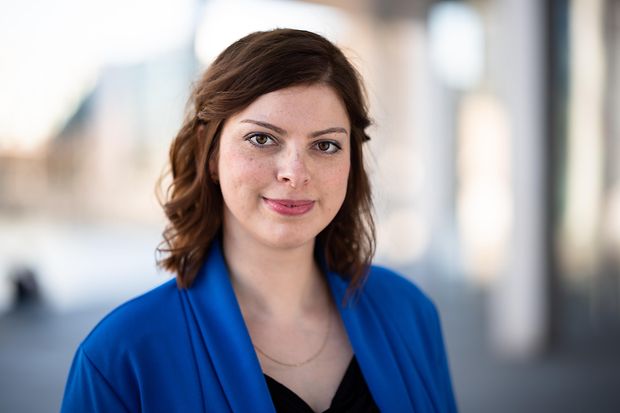 Eine Frau mit dunklen Haaren und blauer Jacke schaut in die Kamera.