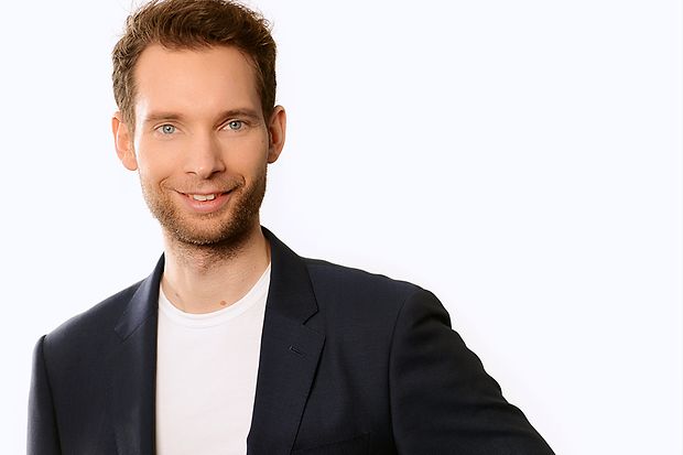 Junger Mann in dunklem Sakko und weißem Tshirt
