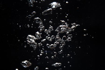 Bubbles and silver particles floating in dark water creating a mesmerizing effect