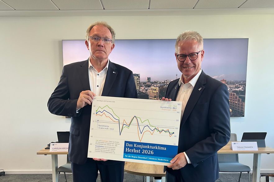 Gregor Berghausen und J&uuml;rgen Steinmetz halten eine Grafik hoch, die das Konjunkturklima im Herbst 2026 zeigt.