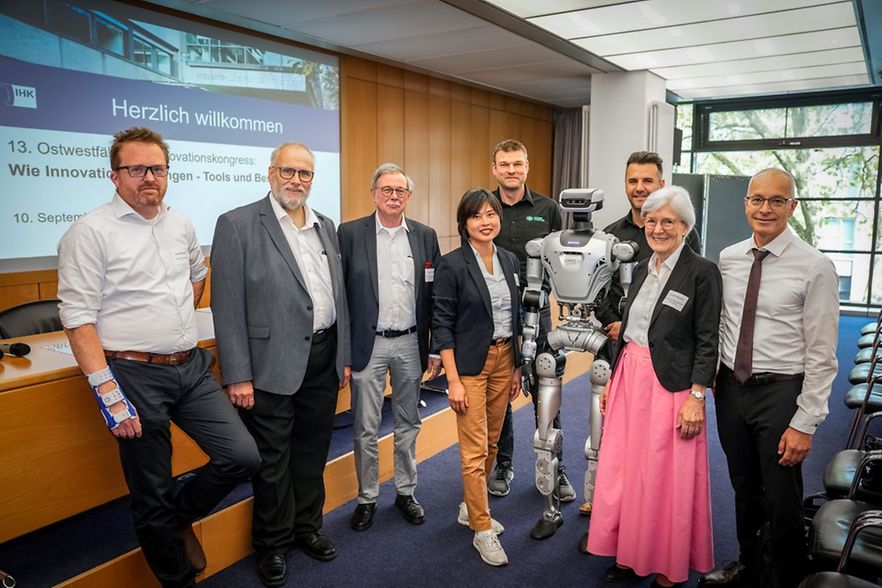 Acht Personen mit humanoidem Roboter beim 13. Ostwestf&auml;lischen Innovationskongress