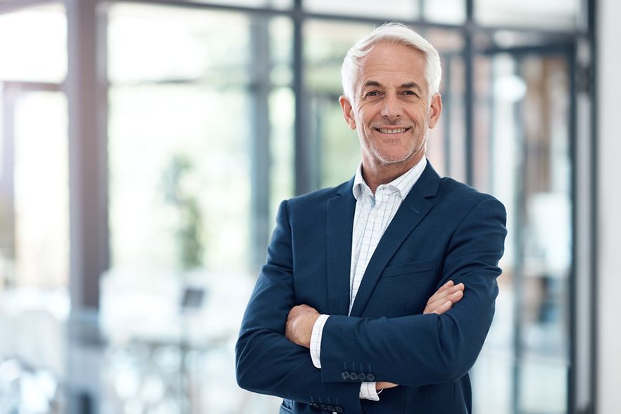 Portrait eines &auml;lteren, l&auml;chelnden Unternehmers im modernen B&uuml;ro