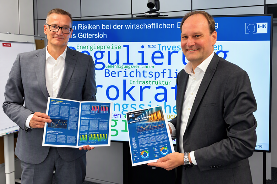 Zwei M&auml;nner pr&auml;sentieren die IHK-Konjunkturumfrage f&uuml;r G&uuml;tersloh.