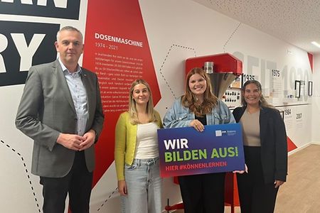 4 Personen mit einem Schild "Wir bilden aus! Hier #k&ouml;nnenlernen"