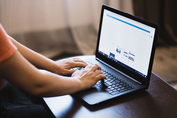 Hände schreiben an einem Laptop